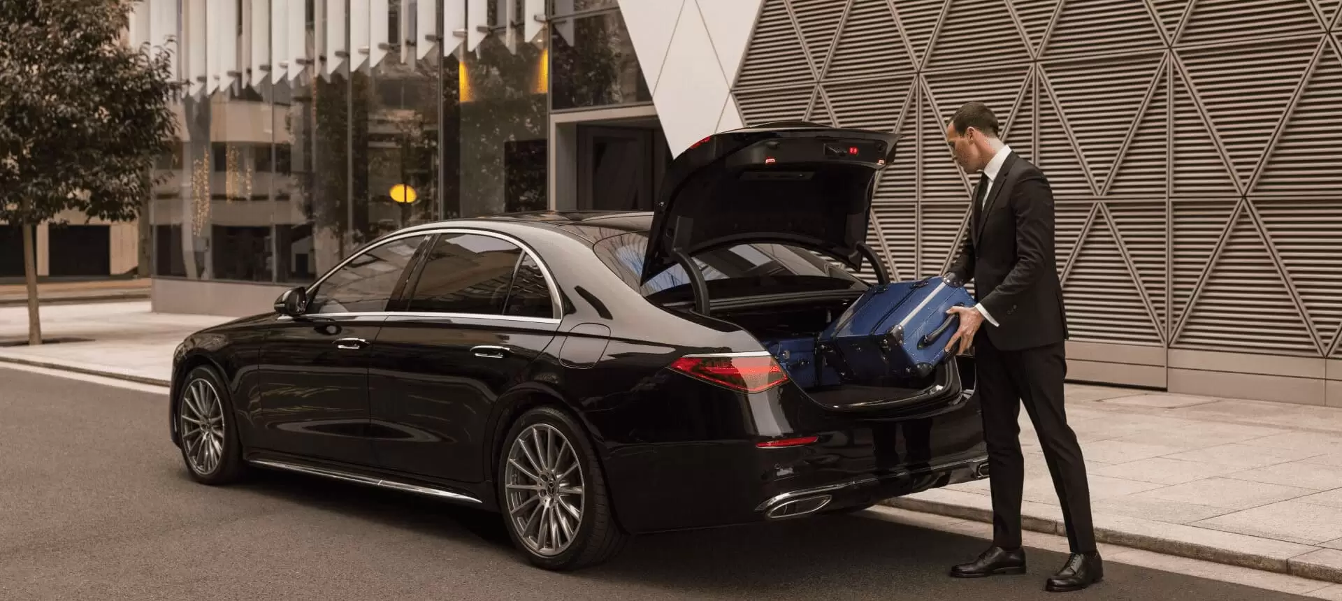 Luema chauffeur loading luggage into a Mercedes-Benz sedan