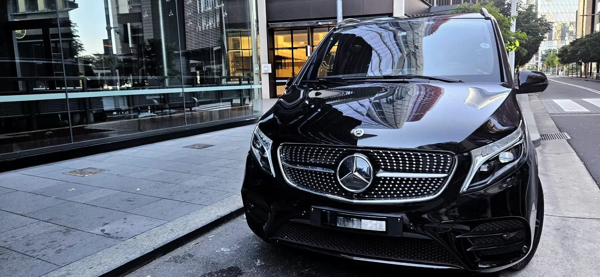 Black Mercedes-Benz V-Class chauffeur vehicle parked outside a Sydney office building